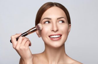 Visage de femme gros plan avec un pinceau de maquillage.  Belle femme portrait beauté peau maquillage sain et parfait.  Femme appliquant un cosmétique avec un pinceau.