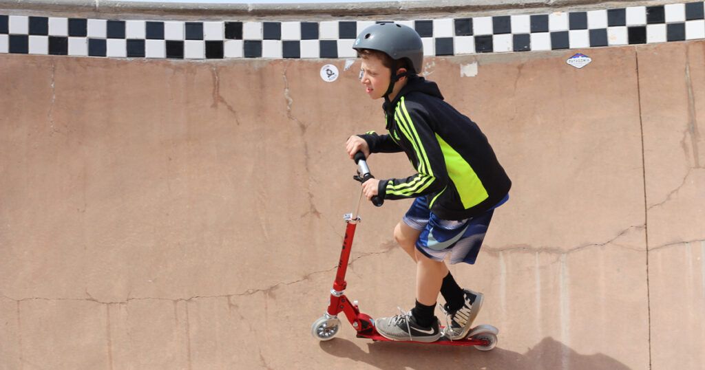 Un garçon sur une trottinette pour enfants Razor dans un skate park.