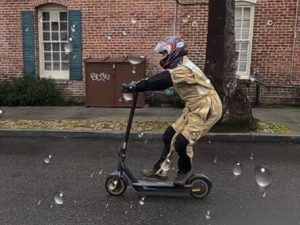 Segway-Ninebot-Max-electric-scooter-man-riding-in-rain-braking-on-scooter-side-shot